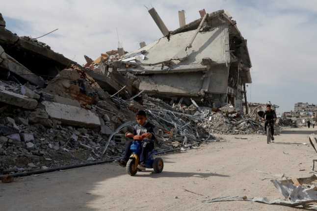 A Palestinian child rides a tricycle infront of a rubble of houses destroyed during the Israeli offensive, in Rafah, in the southern Gaza Strip, March 13, 2025. REUTERS/Hatem Khaled