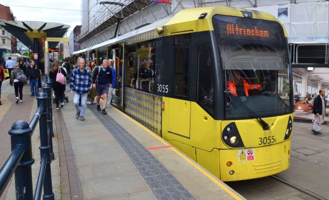 A Metrolink tram to Altrincham sitting at a platform in Manchester.