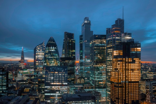 Aerial panoramic view of The City of London cityscape skyline with metropole financial district modern skyscrapers after sunset on night with illuminated buildings and cloudy sky in London, UK