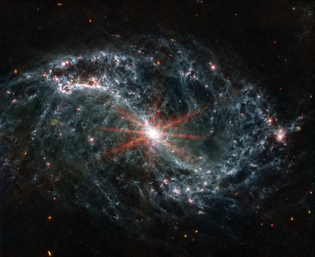Intricate networks of gas and dust featured in the web-like spiral galaxy NGC 7496 are seen in a composite image taken by the James Webb Telescope and released by NASA on February 16, 2023. Eight red diffraction spikes extend out from its extremely bright core. Colorful dots in the background represent background galaxies. NASA/ESA/Handout via REUTERS THIS IMAGE HAS BEEN SUPPLIED BY A THIRD PARTY