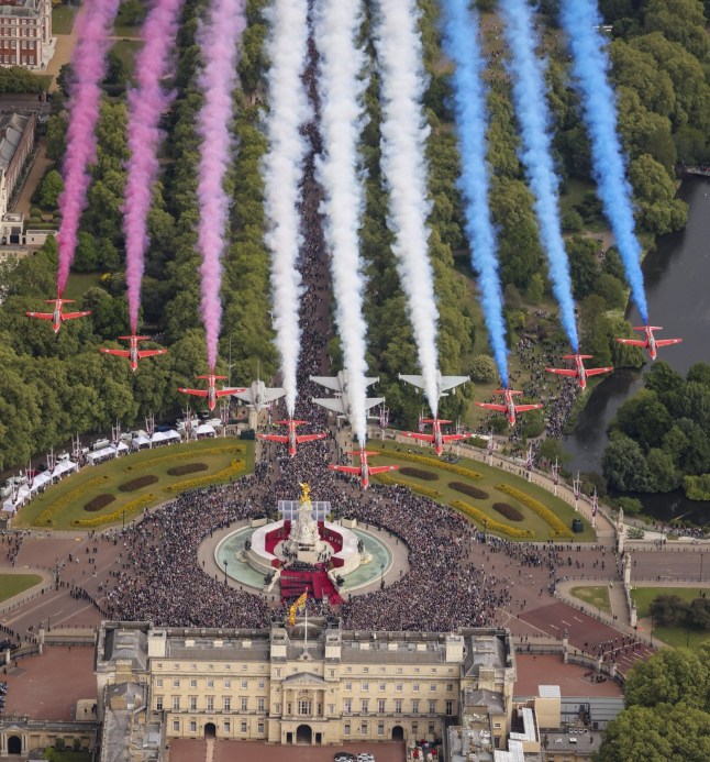 The Red Arrows seen flying over Buckingham Palace in central London on VE Day with crowds below them.