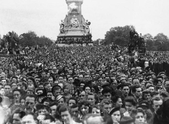 The crowd gathered to celebrate VE Day at the end of the Second World War, waiting to see the Royal Family on the balcony at Buckingham Palace, on The Mall, Westminster, London, England, 8th May 1945. The Victoria Memorial, Sir Thomas Brock's monument to Queen Victoria, is visible in the background. (Photo by Harry Todd/Fox Photos/Hulton Archive/Getty Images)