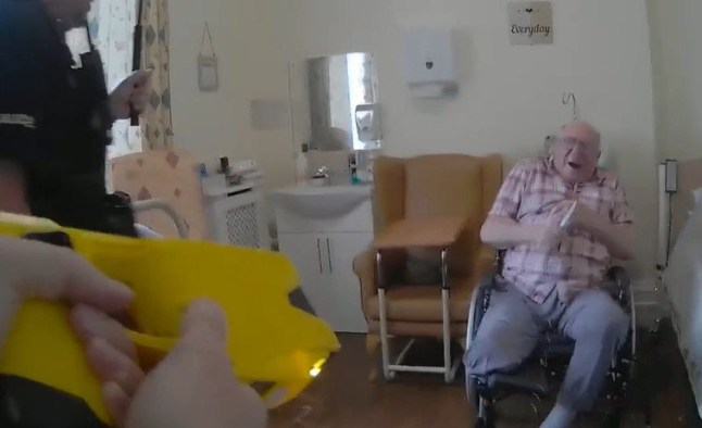 Police officer tasers man sat in chair.