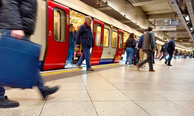 People stepping out of a London Underground train carriage at a Tube station platform.