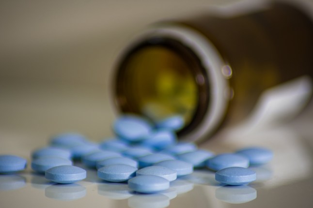 Spilled blue medical pills from brown glass, little tablets helping anti-viruses