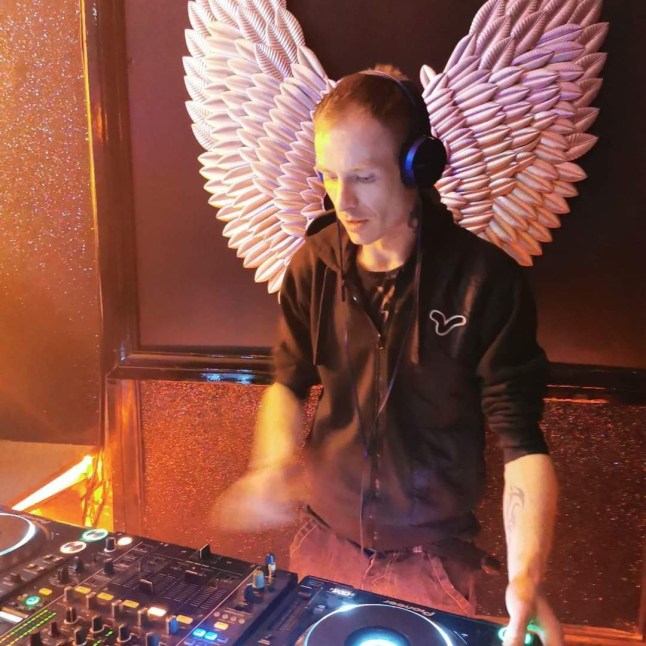 Iain Smith standing at a DJ deck with headphones on.