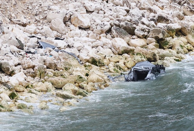 Dramatic pictures show the wreckage of a car which plunged hundreds of feet off a tall cliff. Photos show the twisted metal of the silver vehicle which ended up in the water below. Police, firefighters, paramedics and coastguards all attended the scene following reports of a 'serious incident'. It is understood that a man has been 'recovered' from the water by a lifeboat volunteer. Emergency services were called at around 7.20pm Friday evening to Alum Bay in the Isle of Wight, Hants. Police have confirmed the death of two people after a car plunged off a cliff. SEE OUR COPY FOR DETAILS. Please byline: Darren Toogood/Island Echo/Solent News ?? Darren Toogood/Island Echo/Solent News & Photo Agency UK +44 (0) 2380 458800