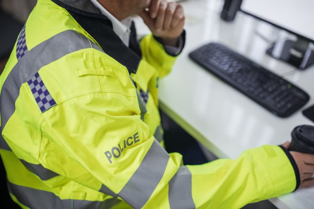 One senior traffic warden sitting at the office in front of the computer and drinking coffee