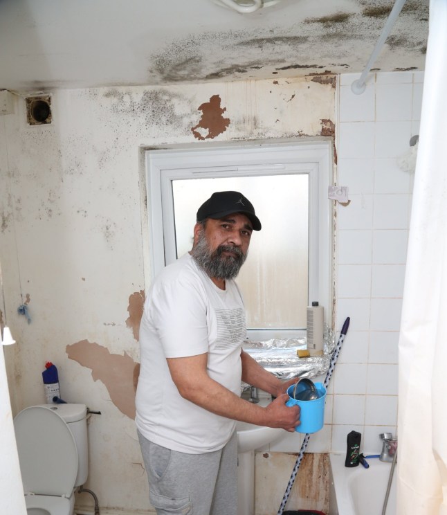 Sanjay standing in his mouldy bathroom.