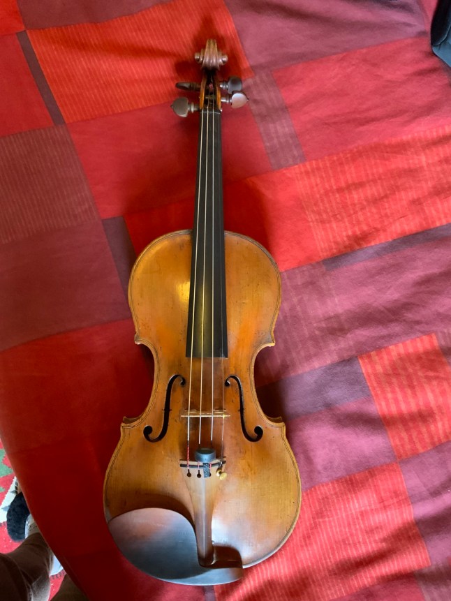 The violin laid on a red and purple cloth.