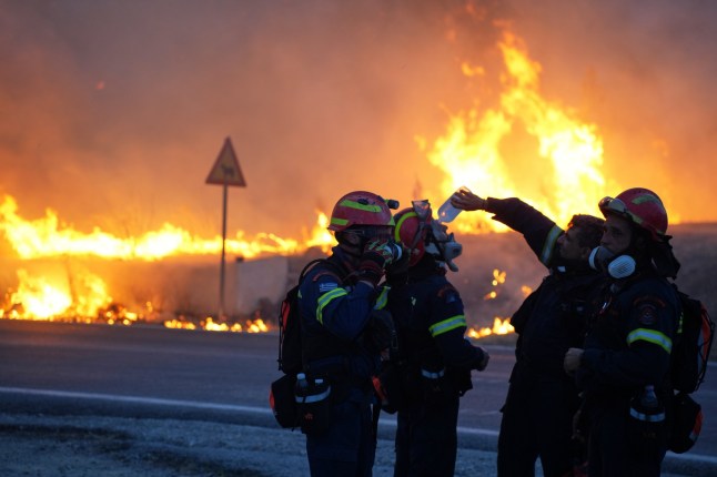 A firefighter pours water to cool down his colleague as they battle with a large wildfire burning in Karyes village, on the eastern Aegean island of Chios, Greece, Sunday, June 22, 2025. (Pantelis Fykaris/Politischios.gr via AP)