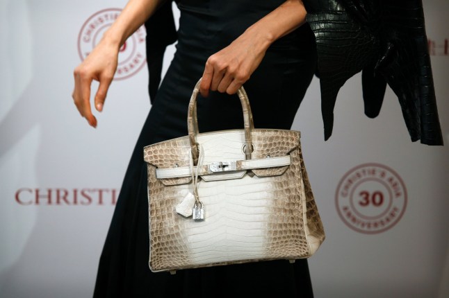 Eunis Chan models a Matte White Himalaya Niloticus Crocodile Diamond Birkin with 18K gold and diamond hardware -- one of the most valuable handbags in the world -- during a preview at Christies in Hong Kong on May 4, 2016. / AFP / ISAAC LAWRENCE (Photo credit should read ISAAC LAWRENCE/AFP/Getty Images)