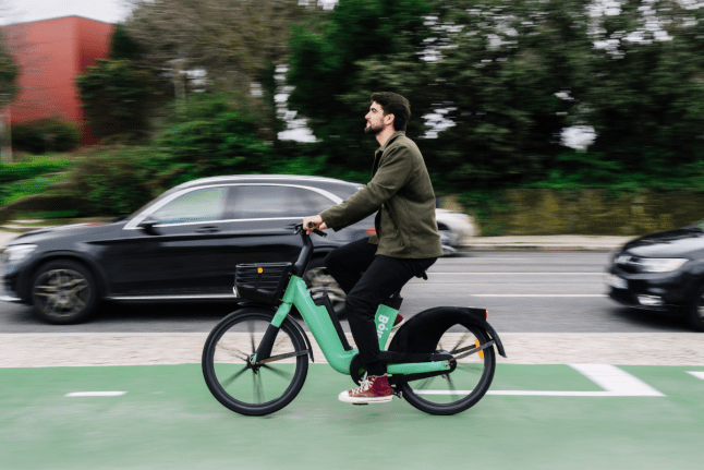 A man riding a Bolt e-bike with cars on the background.