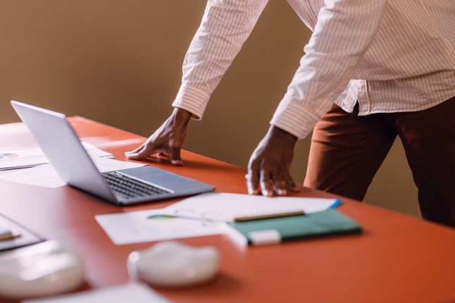 Professional Worker Using Laptop at Business Desk with Documents