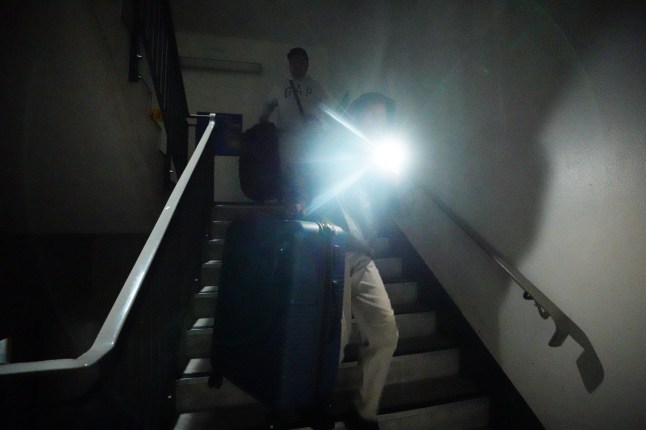 Stranded passengers makes their way down unlit stairs due to lifts not working to the car park at Heathrow Terminal 4 in London. More than 1,300 flights to and from Heathrow Airport will be disrupted on Friday due to the closure of the airport following a fire at the North Hyde electrical substation last night. Picture date: Friday March 21, 2025. PA Photo. See PA story FIRE Hayes. Photo credit should read: James Manning/PA Wire