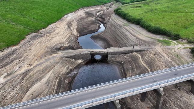 Low water levels at Baitings Reservoir reveal an ancient pack horse bridge in Ripponden, England