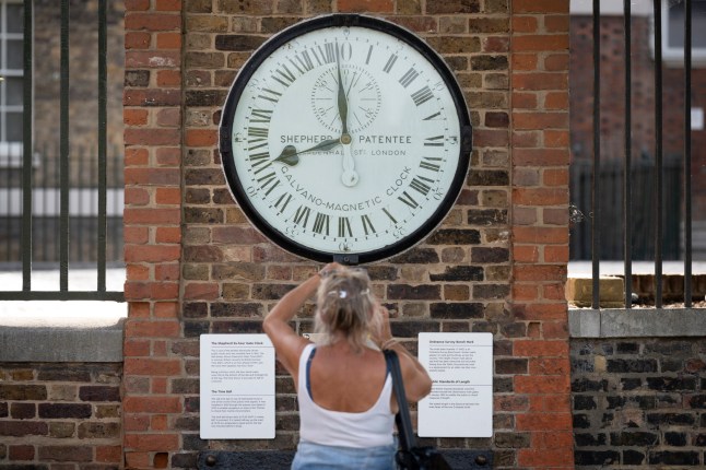 A visitor to the Royal Observatory, takes a photo of the Gate Clock at the Greenwich Meridian in Greenwich Park, on 16th June 2022, in London, England. Greenwich Park is a former hunting park and one of the largest single green spaces in south-east London. (Photo by Richard Baker / In Pictures via Getty Images)