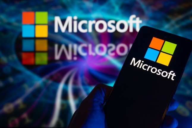 The Microsoft logo is being displayed on a smart phone with Microsoft visible in the background in this photo illustration, in Brussels, Belgium, on December 30, 2023. (Photo by Jonathan Raa/NurPhoto via Getty Images)