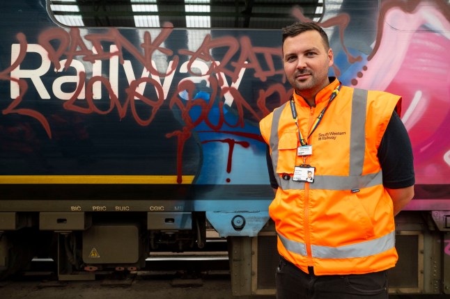 The head of SWR's train presentation team, Charlie Hatcher in front of a graffitied train carriage.