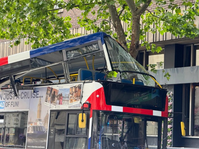 A hop-on hop-off London tour bus packed with tourists has crashed in central London, just yards from the historic 7/7 bomb site, injuring several people and triggering a major emergency response. The collision occurred at around 2:40pm this afternoon, when the open-top double-decker bus struck a tree during a sightseeing route near Tavistock Square. The force of the impact crumpled the roof of the upper deck, trapping at least six people, including a young girl, inside the mangled wreckage. Emergency Services Rush to the Scene Multiple fire engines, ambulances, and paramedic units from the London Ambulance Service and London Fire Brigade rushed to the scene. Firefighters used specialist cutting tools to free the trapped passengers, working urgently to secure the damaged upper deck. Witnesses described scenes of ???carnage onboard???, with the bus suddenly jolting and a loud bang echoing across the area. ???I thought a bomb had gone off,??? said one nearby shop worker. ???The noise was horrific ??? metal twisting, glass shattering ??? total chaos. Then people started screaming.??? Location: Near Tavistock Square The crash occurred near Tavistock Square, the site of the devastating 2005 London bus bombing, heightening alarm among those nearby. Police quickly cordoned off the area, reassuring the public that this incident was unrelated to terrorism. Sightseeing Tour Turns to Panic The bus was part of a Hop-on Hop-off sightseeing tour, popular with visitors wanting to explore iconic landmarks at their own pace. It is understood the vehicle collided with a low-hanging tree while in motion, causing catastrophic damage to the roof section. The London Fire Brigade confirmed that the vehicle was made safe shortly after the incident. ??Investigation Underway The Metropolitan Police???s Commercial Vehicle Unit, along with Roads and Transport Policing Command, has launched an investigation into the cause of the crash. Engineers are examining the bus, and CCTV fo