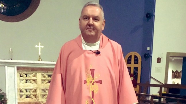 Father Pat Brennan posing for a photo in a church.