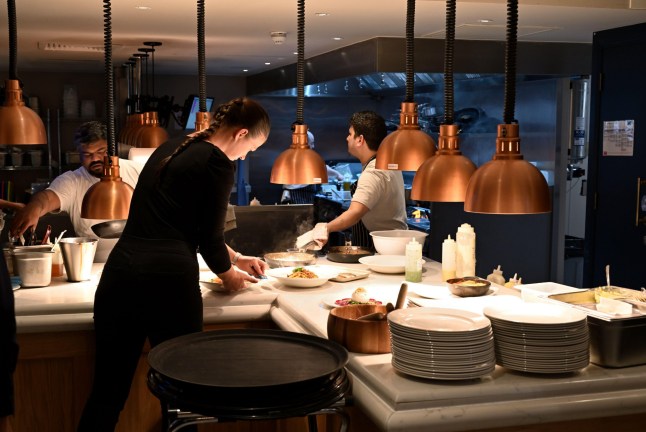 2T4JY0F Restaurant chefs serving area with waitress collected food which is ready, Gusto Italian, Oxford, UK