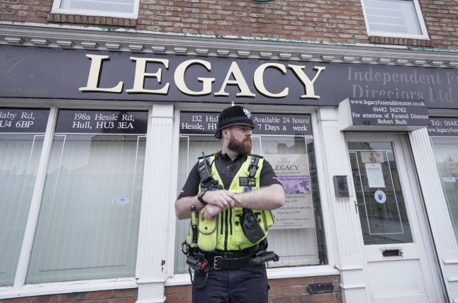 A police officer standing keeping guard outside the Legacy Funeral Directors' site.