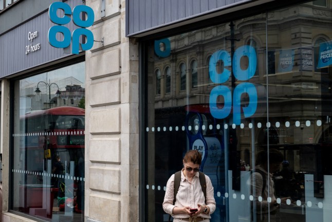 A pedestrian looks at their phone in front of a Co-op store on the Strand, after the group said hackers had accessed and extracted customer data from one of its systems as it continued to experience a sustained cyber attack, in London, Britain, May 3, 2025. REUTERS/Chris J. Ratcliffe