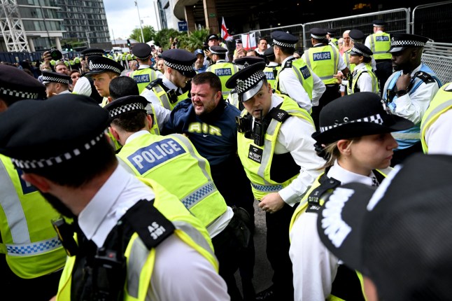 A man reacts after being arrested during a demonstration outside the Britannia Hotel in Canary Wharf on August 3, 2025 over it's use to house asylum seekers. (Photo by JUSTIN TALLIS / AFP) (Photo by JUSTIN TALLIS/AFP via Getty Images)