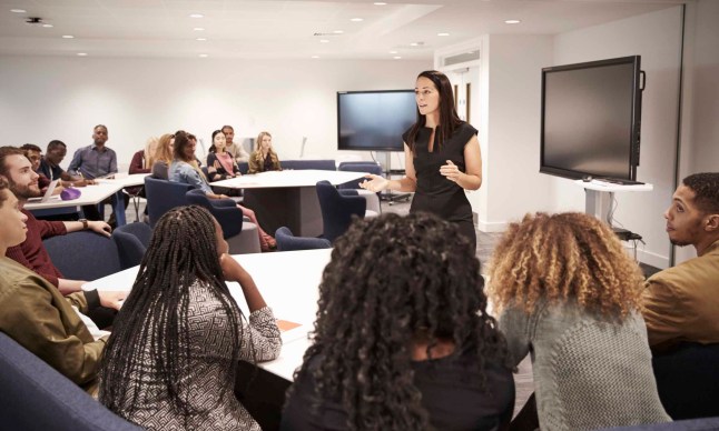 Female teacher addressing university students in a classroom