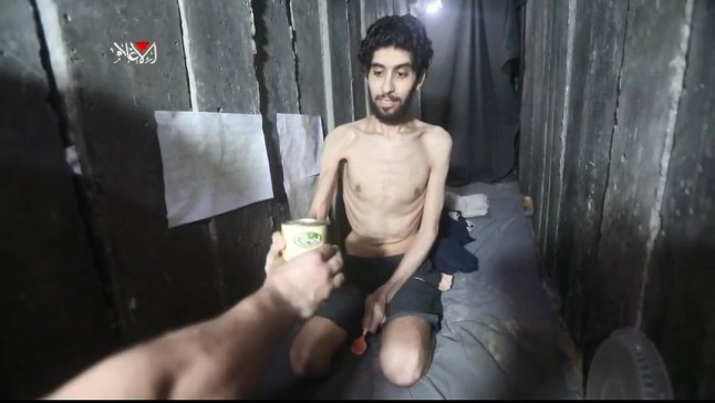 A captor appears to pass Evyatar David a can, in a tunnel in Gaza as hostage looks to be suffering starvation / Source: