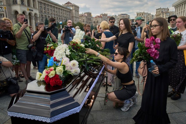 Colleagues and friends lay flowers on the coffin of Victoria Roshchyna, 27, a Ukrainian journalist who reported on the Russian invasion of Ukraine and died in Russian captivity, during the funeral ceremony in the Independence square in central Kyiv, Ukraine, Friday, Aug. 8, 2025. (AP Photo/Efrem Lukatsky)