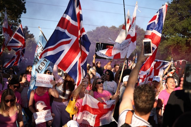 Protesters calling for the closure of The Bell Hotel, believed to be housing asylum seekers, gather outside, in Epping, northeast of London, on August 8, 2025. (Photo by HENRY NICHOLLS / AFP) (Photo by HENRY NICHOLLS/AFP via Getty Images)
