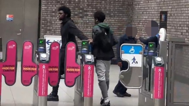Screengrabs of a video showing two fare dodger walk through ticket barriers at Woolwich station.