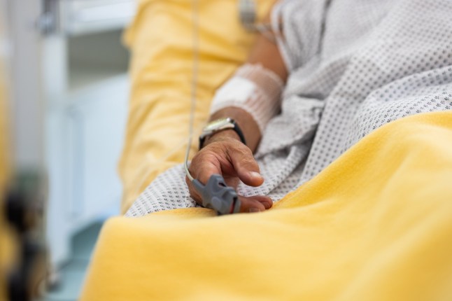 Close-up of a male patient's hand in a hospital bed with oximeter. Senior man admitted hospital.