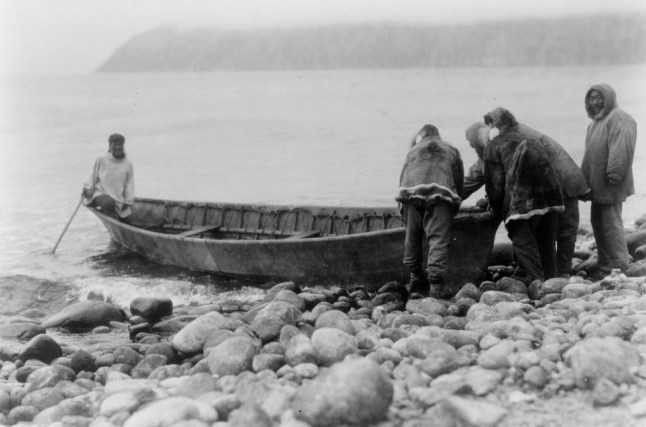 Launching the boat-Little Diomede Island, circa 1928. Group of men launching boat from rocky shoreline. Creator: Edward Sheriff Curtis. (Photo by Heritage Art/Heritage Images via Getty Images)