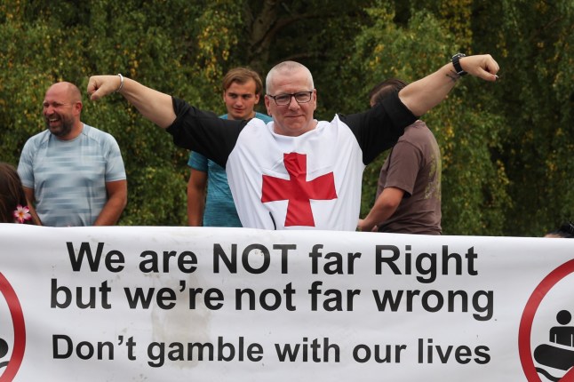 ?? Licensed to London News Pictures. 14/08/2025. Epping, UK. Man dressed as a English Knight stands behind a large banner, as local residents hold an anti-migrant protest outside The Bell Hotel, Epping. A Syrian man who is staying at the hotel, which houses asylum seekers, has appeared in court charged with sexual assault. He is the second asylum seeker from the hotel to be charged with sexual assault in recent weeks. Photo credit: Jacqueline Lawrie/LNP