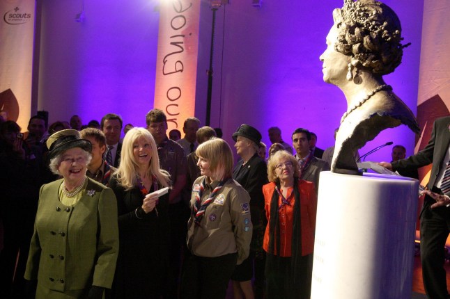 Britain's Queen looks at a bronze statue of herself created by sculptor Frances Segelman (second left) at the Scout Association Activity Centre at Baden-Powell House, London.