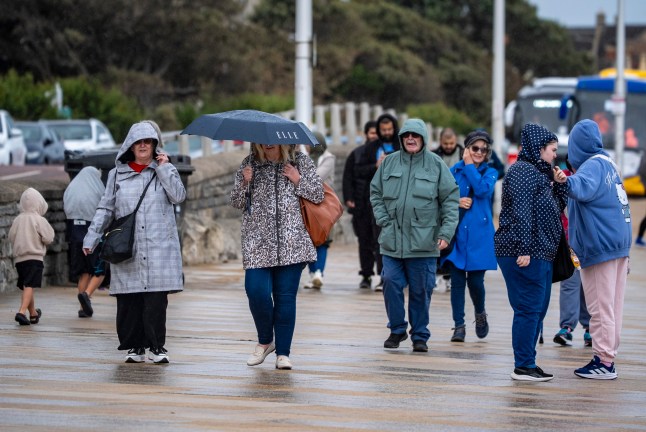 Umbrellas come out on the promenade at Weston-super-Mare, Somerset, where stormy skies, wind and rain move in over the south west as temperatures dip across the UK. Picture date: Wednesday August 27, 2025. PA Photo. Photo credit should read: Ben Birchall/PA Wire