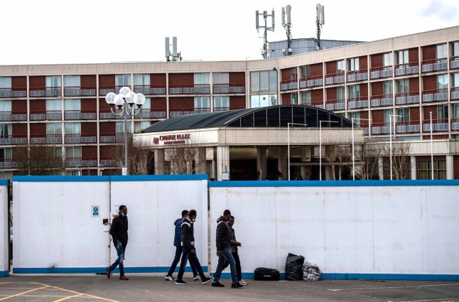 LONDON, ENGLAND - FEBRUARY 24: Asylum seekers exit the Crowne Plaza hotel through an exterior perimeter wall that has been installed whilst they stay at the hotel on February 24, 2021 in London, England. Last week, a group of asylum seekers staying at the Crowne Plaza hotel held a demonstration outside to protest the conditions and the length of the asylum claims process. (Photo by Chris J Ratcliffe/Getty Images)