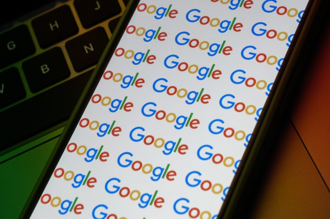 A close up photo of a mobile phone with the word 'Google' repeated on the screen.