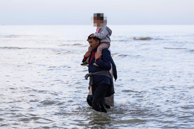 Migrants walk back after failing to board a smuggler's boat in an attempt to cross the English Channel off the beach of Gravelines, northern France on August 12, 2025. (Photo by Sameer Al-DOUMY / AFP) (Photo by SAMEER AL-DOUMY/AFP via Getty Images)