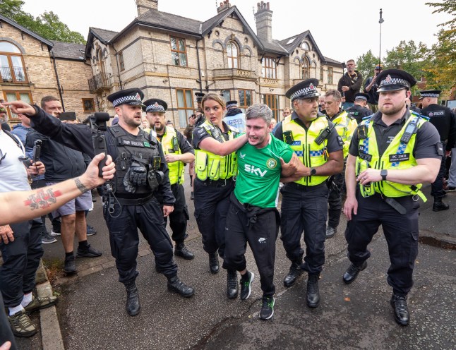 An anti migrant protester is held by police before being removed and taken away. Arrests at migrant hotel protest Manchester UK. Sunday saw continuing protests at 'Manchester South Hotel' in Fallowfield Manchester. Anti migrant hotel protesters faced antifacist protesters accross the road. Flags were raised on lamp posts and police held streamers and vloggers back from interacting with antifacist protesters. Several anti migrant hotel protesters were arrested and led away by police. Fallowfield Manchester. Picture: garyrobertsphotography Migrant Hotel protest, Manchester, UK - 07 Sep 2025